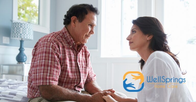 A daughter who is caregiving for her dad who has Alzheimer’s disease, lovingly holds his hands.